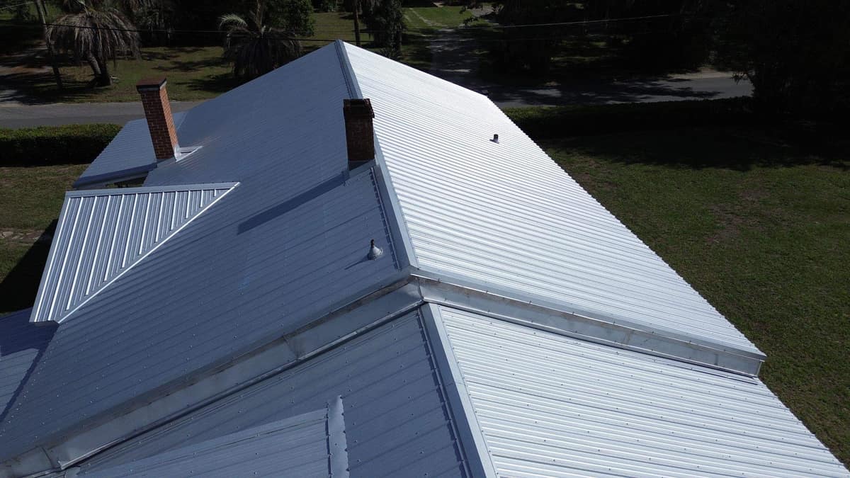 Drone view of the new light gray metal roof and two brick chimneys on an Alachua home