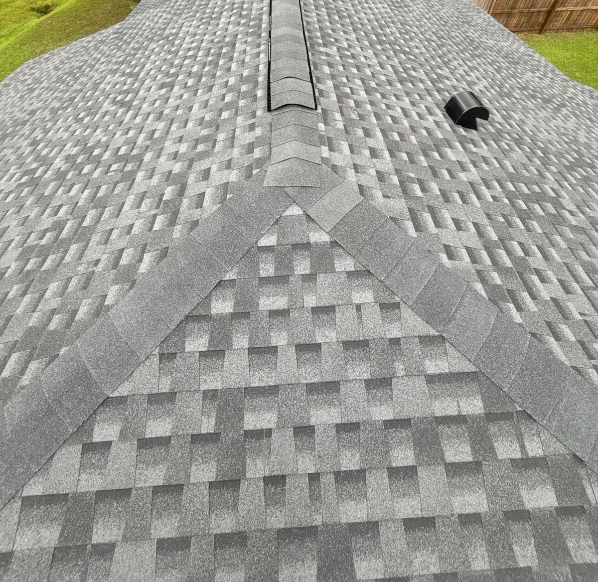 Looking along the main ridge vent from the hip end of the new gray shingle roof in Alachua