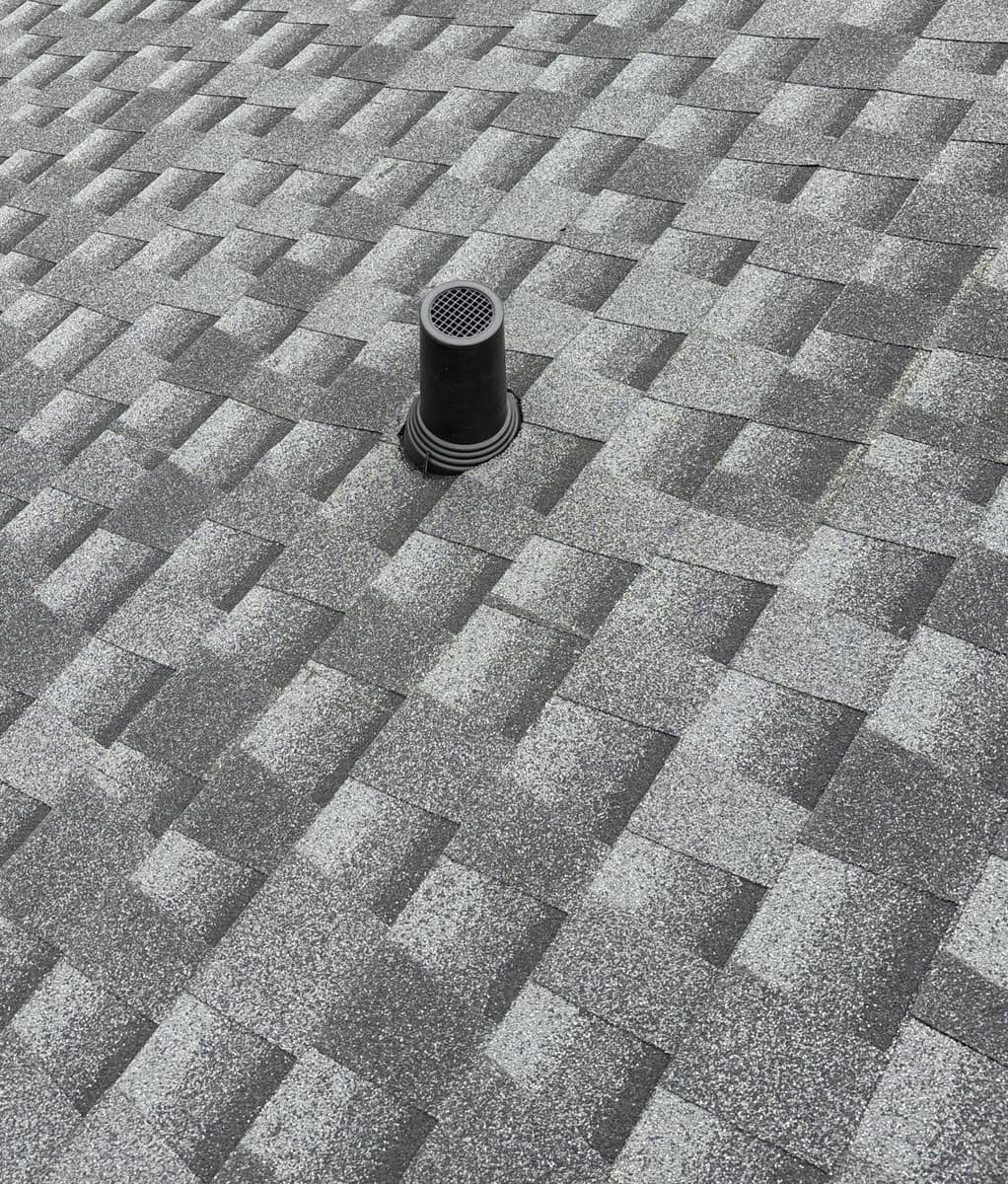 Black vent pipe with a screened top and a ribbed boot at the shingles in Alachua