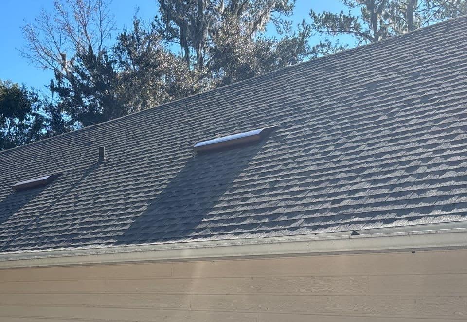 New gray architectural shingles on the garage wing of an Alachua home, with two long, low metal vents
