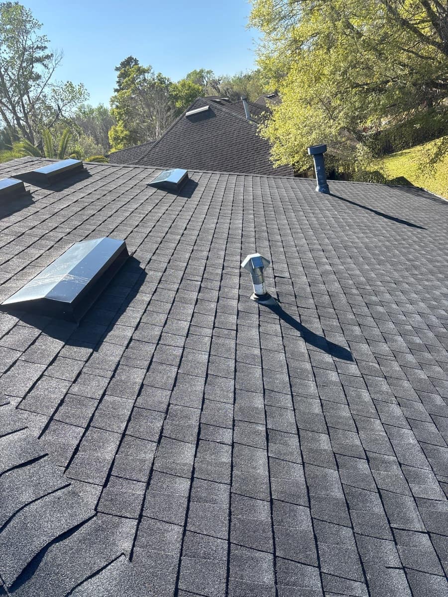 Four skylights, a metal vent and a tall dark vent stack on one slope in Alachua