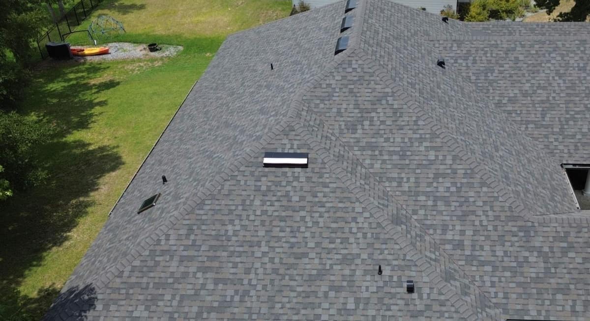 Drone view of the new gray shingle hip roof and shaded side lawn of an Alachua home