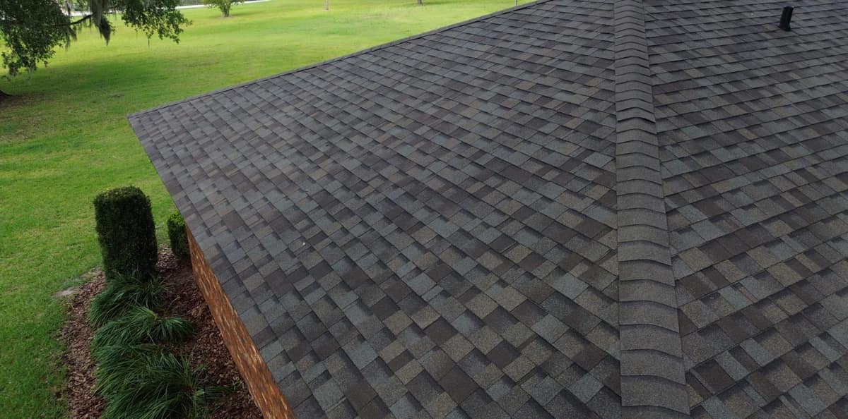 Drone view of new brown and gray shingles along a hip ridge of a brick home in Alachua