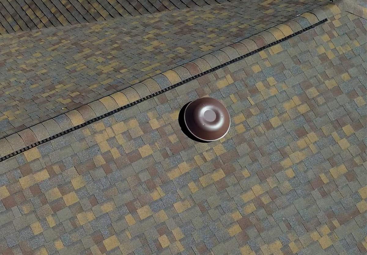 Close view of a ridge vent under rounded cap shingles beside a brown dome vent in Alachua