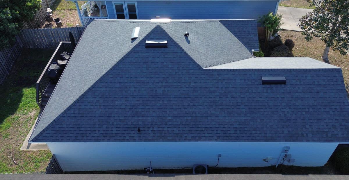 Side of the Alachua home, with the new roof above white walls and a fenced yard