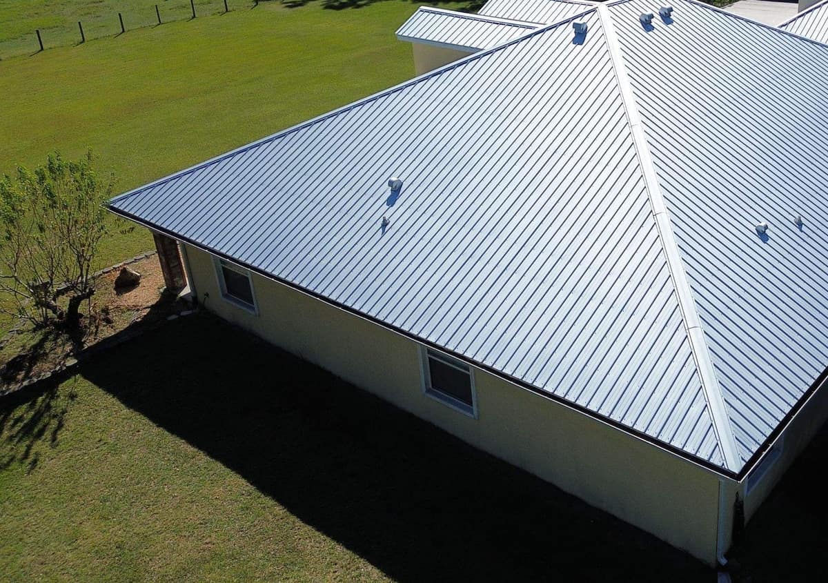 Back corner of the Archer home with its new metal hip roof and pasture fencing beyond