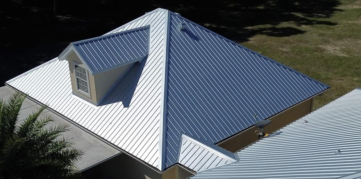 Hip roof over the garage wing in Archer with a single dormer and new metal panels