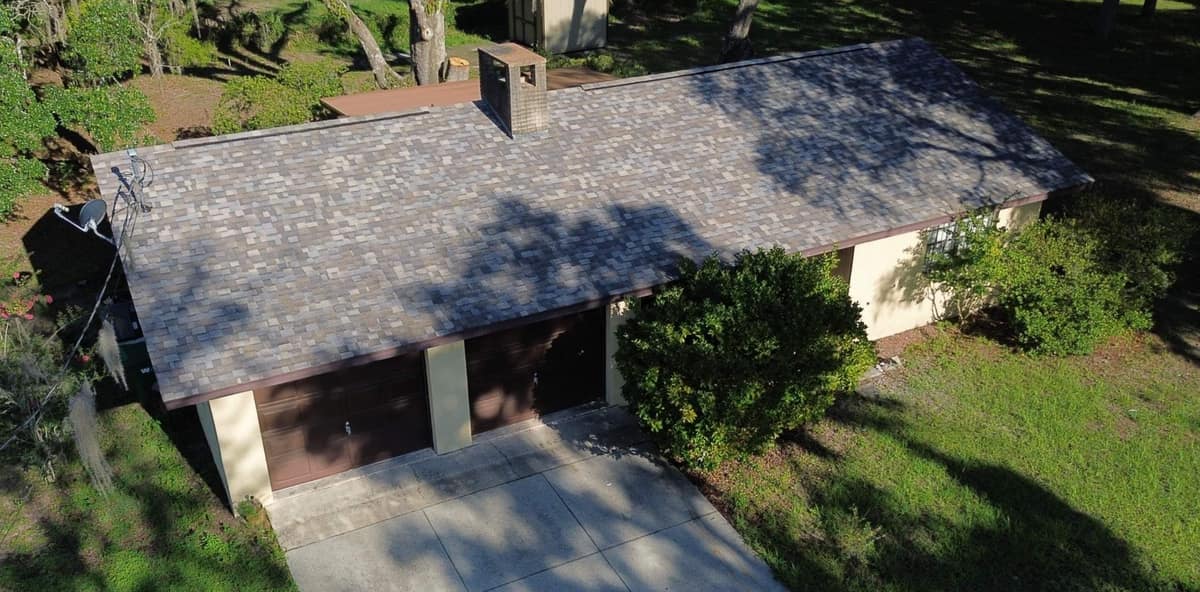Drone view of the new gray and tan shingle roof on a stucco home in Dunnellon