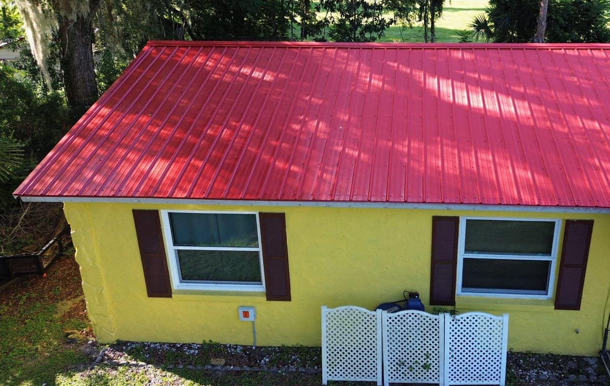 Front of the Fruitland Park home with red metal panels above yellow walls and brown shutters