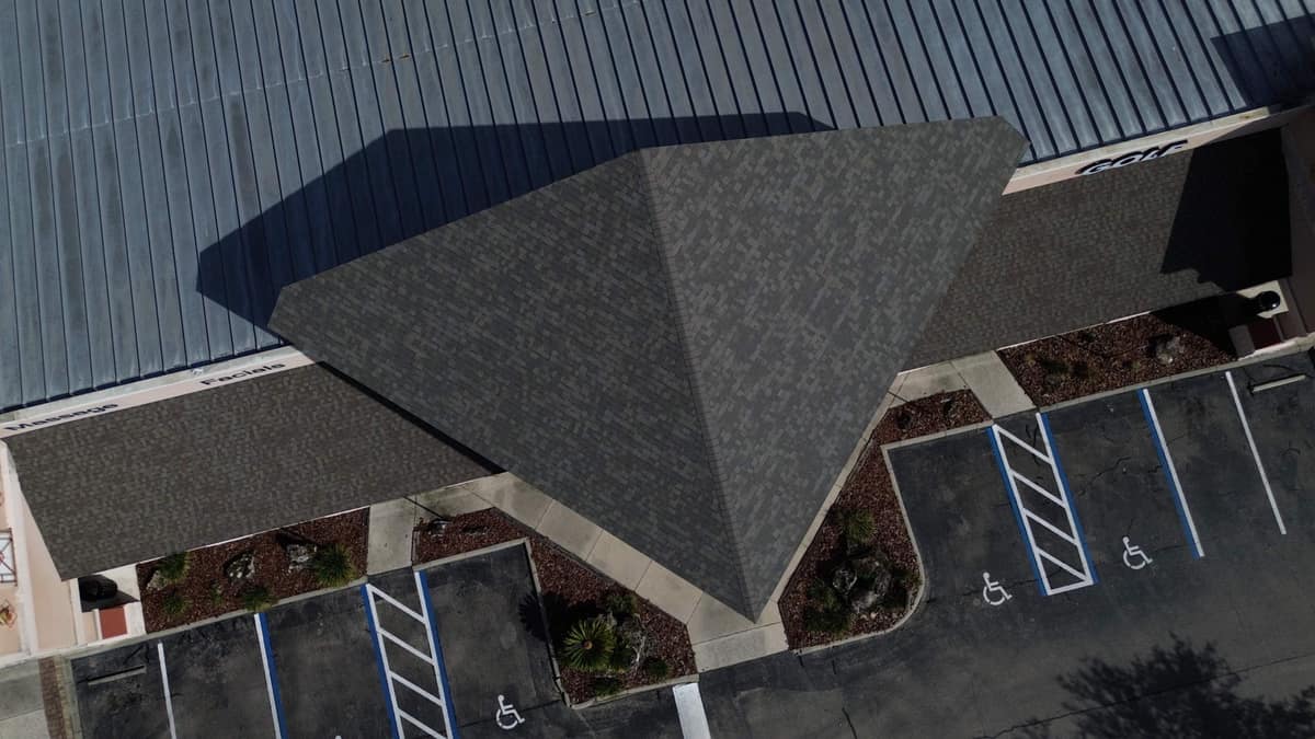 Shingled tower roof rising above the light gray metal roof of a one-story Gainesville building