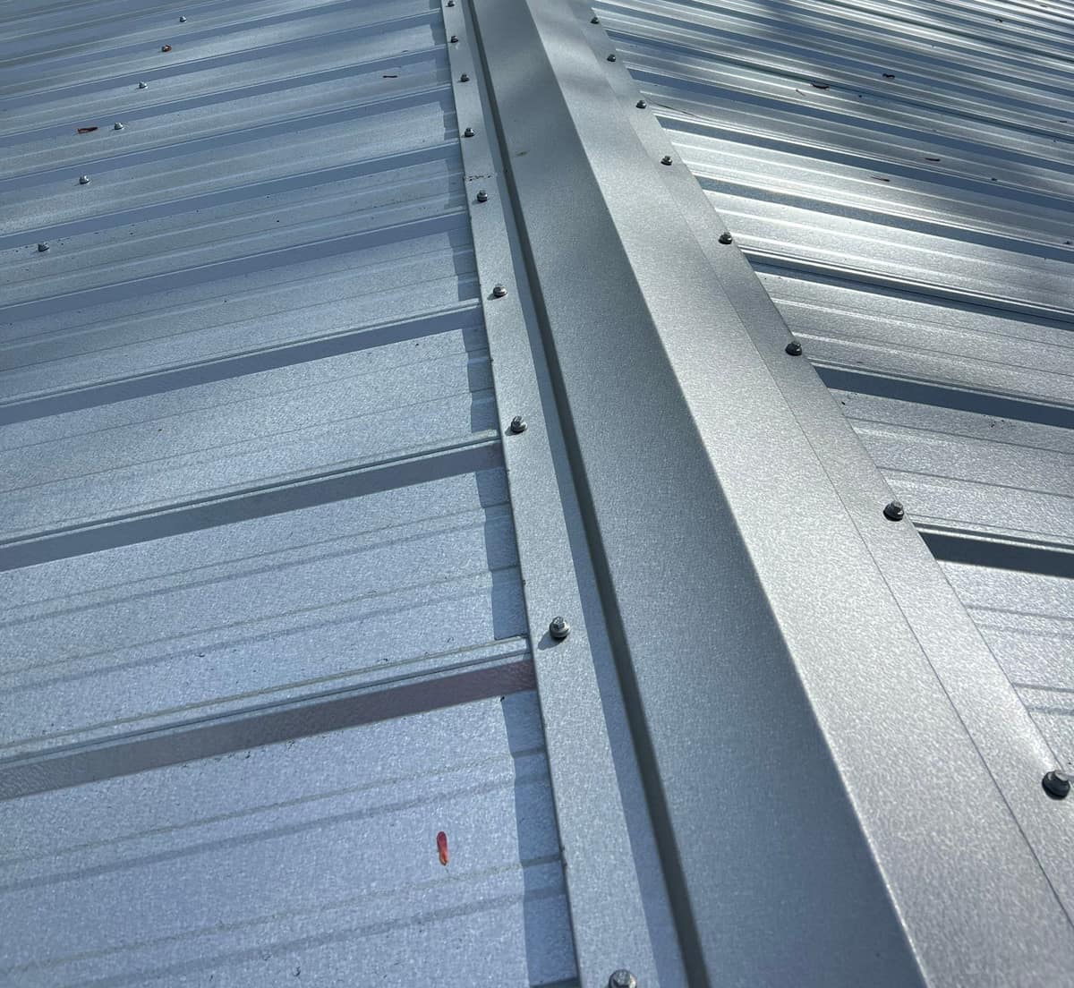 Ridge cap running between both slopes of the new silver-gray metal roof on a Gainesville home
