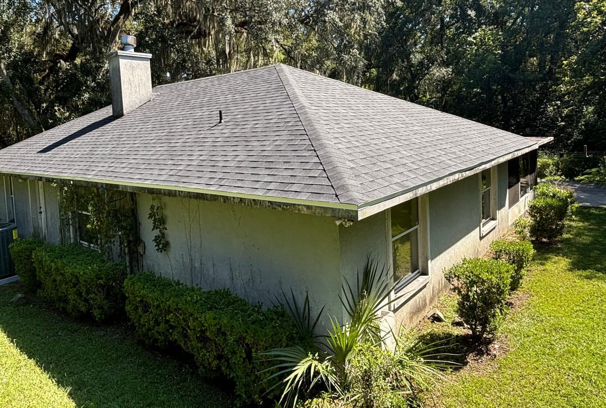 Hip roof with new dark gray architectural shingles on a single-story stucco home in Gainesville