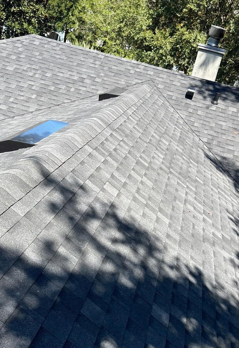 Roof-level view along a hip toward the chimney, with black off-ridge vents, in Gainesville