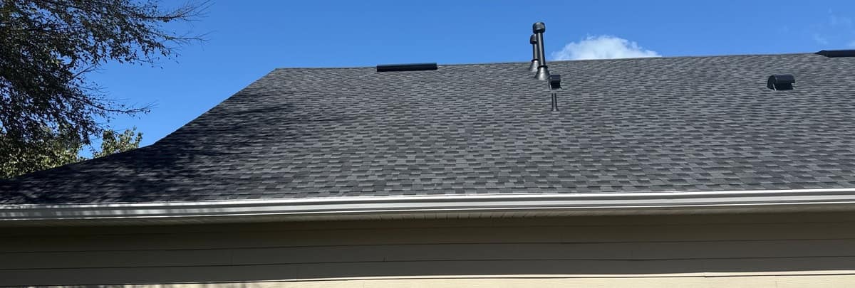 Side of the Gainesville house seen from the yard, new gray roof above tan lap siding