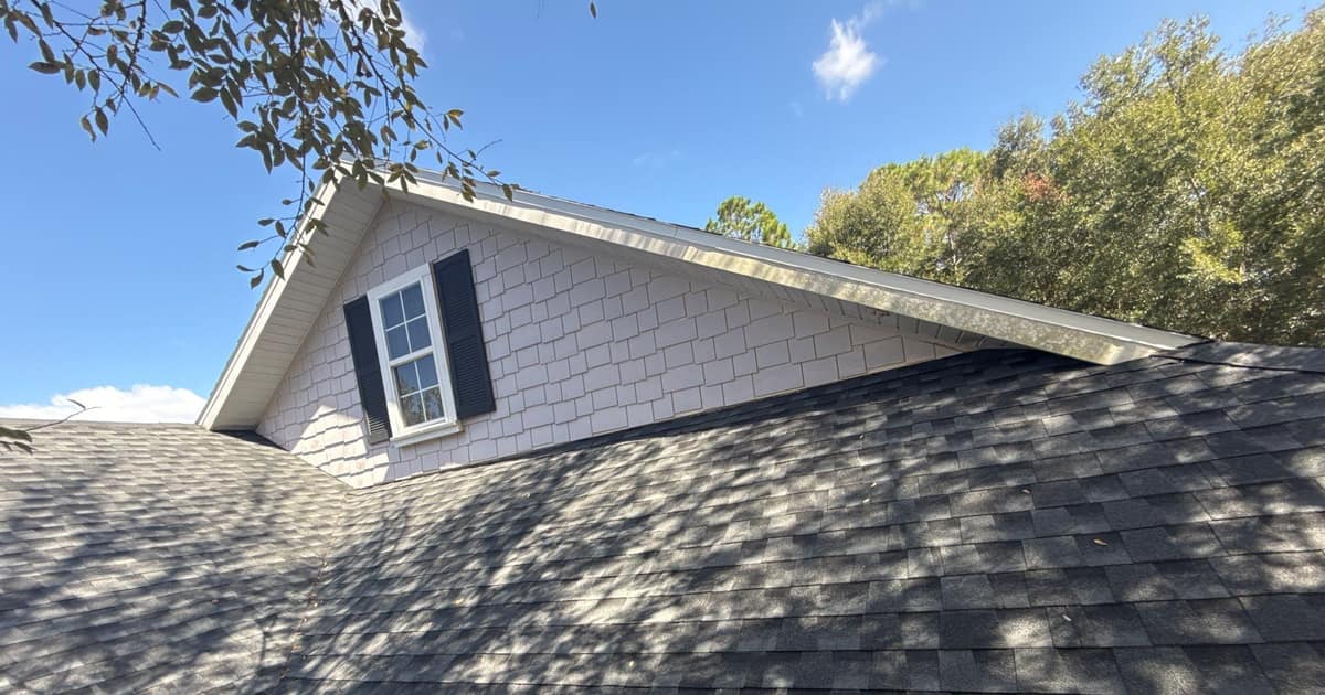 Raised gable in white shake-style siding with black shutters rising above the new shingles in Gainesville