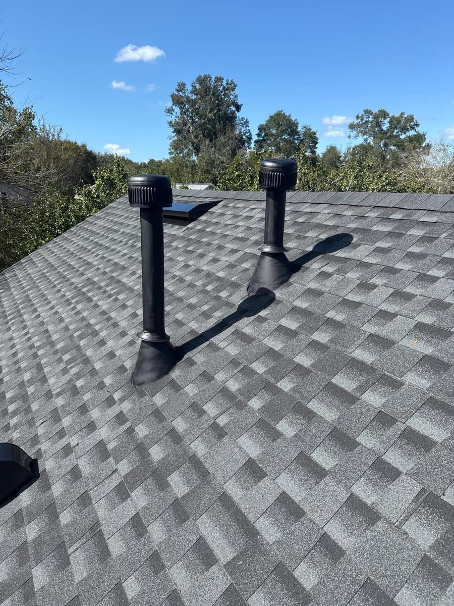 Two tall black vent pipes with ribbed caps and boots on the new Gainesville roof