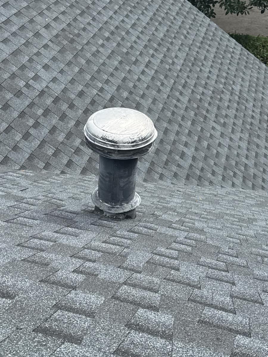 Round domed roof vent on a black collar set into the new gray shingles in Gainesville