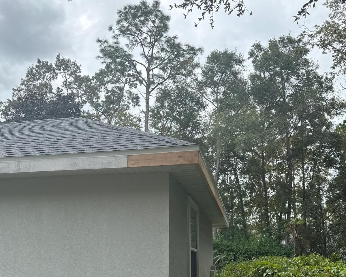Hip corner of one wing with a new fascia section under tall pines and oaks in Gainesville