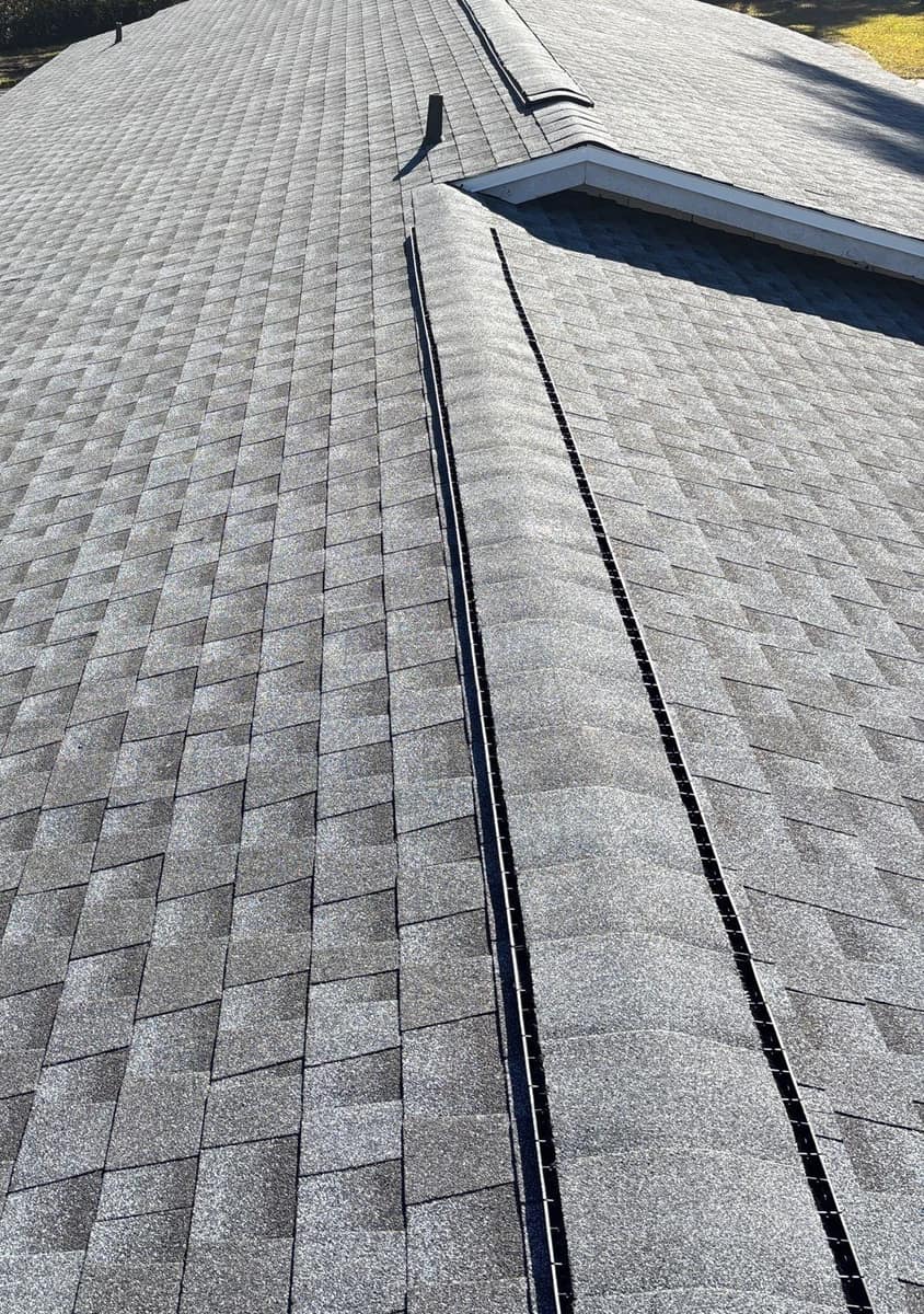 Roof-level view of new gray shingles and a ridge vent on a Gainesville ranch home