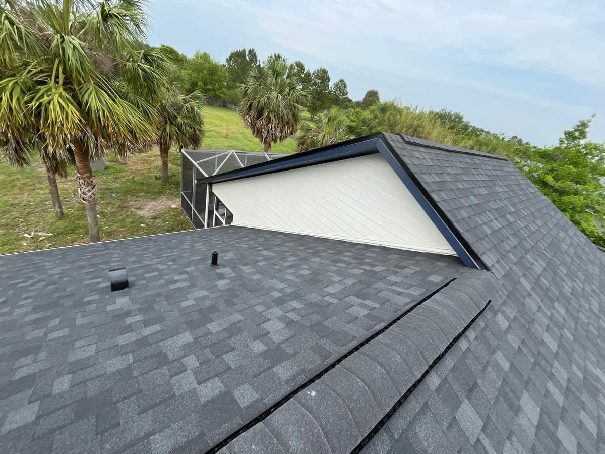 Back of a Gainesville home with a new charcoal gray shingle roof, a white gable and navy trim