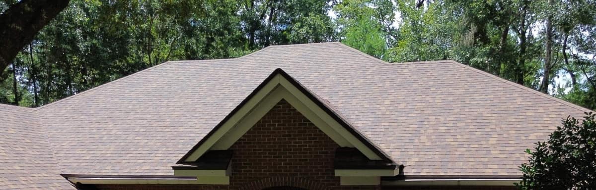 Front entry gable with cream trim and red brick under the new roof in Gainesville