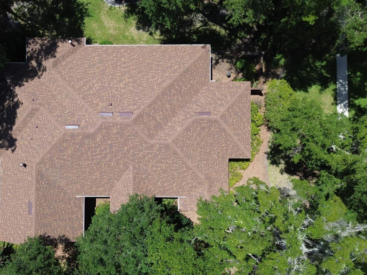 Straight-down drone shot of the whole Gainesville roof surrounded by mature trees