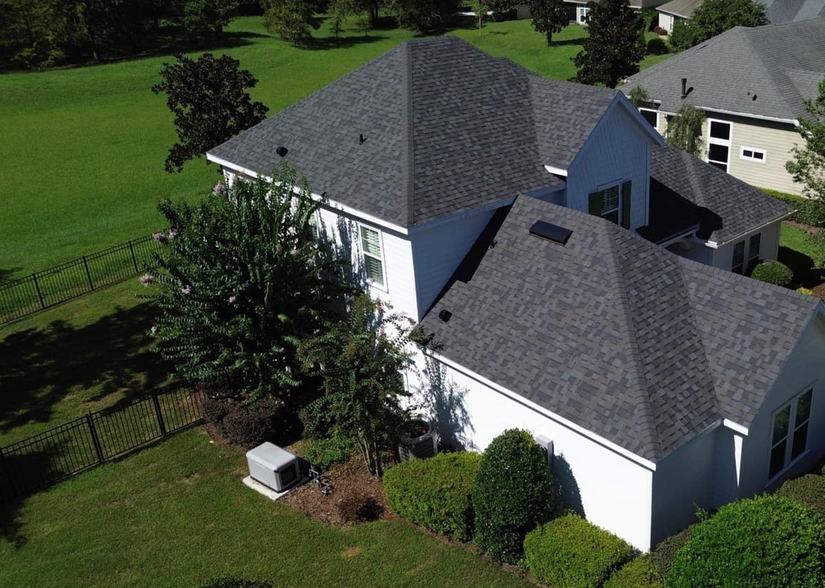 Gainesville home from above with the skylight wing, a fenced yard and open lawn behind