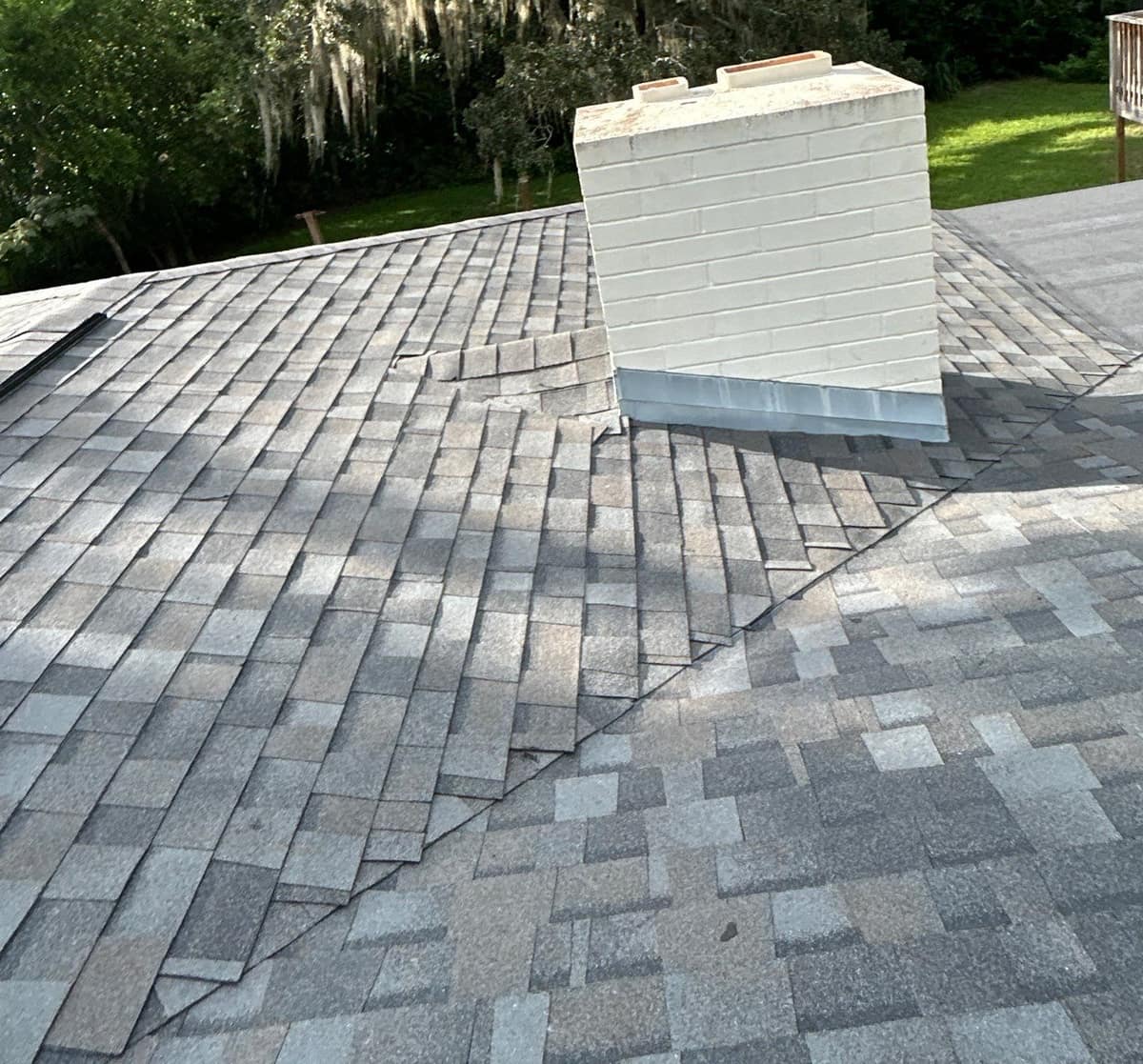 White painted brick chimney with metal flashing beside a trimmed shingle valley on the Gainesville roof