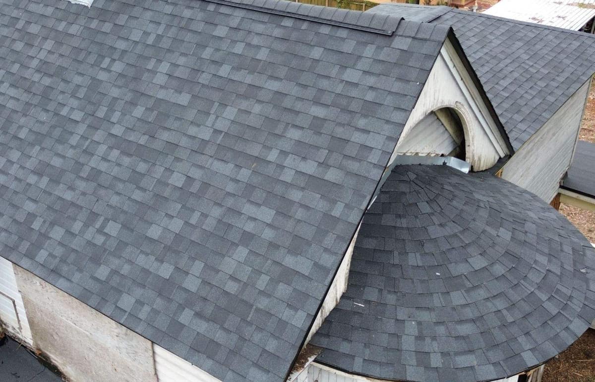 Cone-shaped shingle roof over a round bay beside an arched gable at the back of the Gainesville house