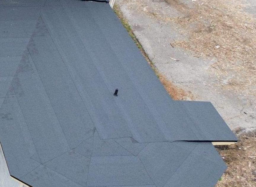 Granulated low-slope roofing in overlapping strips with a vent pipe on the back wing in Gainesville