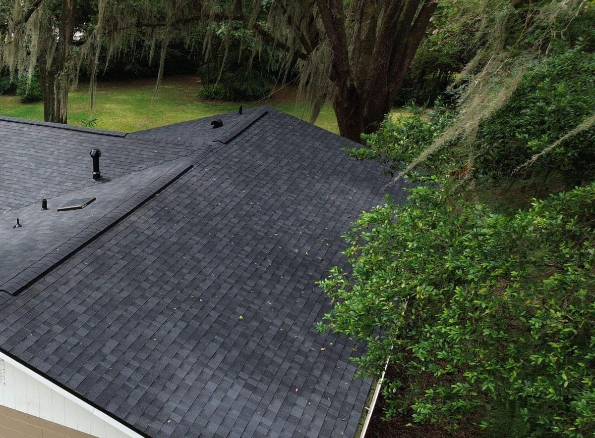 Cross wing ridge with a ridge vent above a white gable end on the Gainesville roof