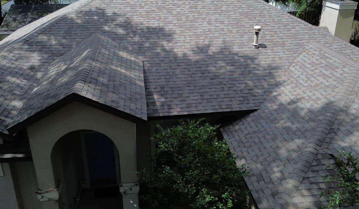 Drone view over the arched entry of a Gainesville stucco home with its new multi-tone shingle roof