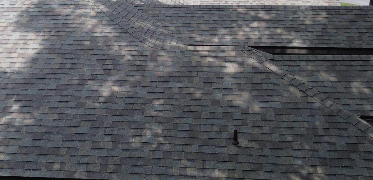Side slope of the Gainesville house with capped hips, a pipe vent and lower roofs stepping down
