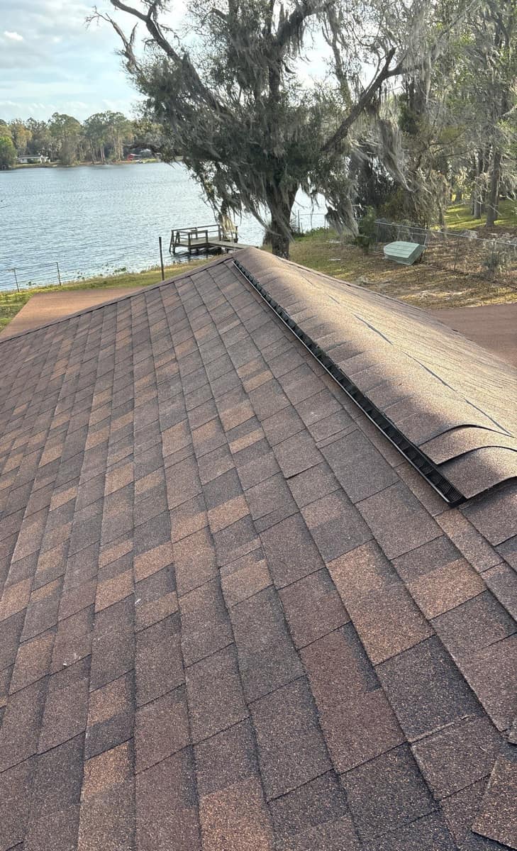 New brown blend shingles and a ridge vent on a Hawthorne lakeside single-story home, with a dock beyond