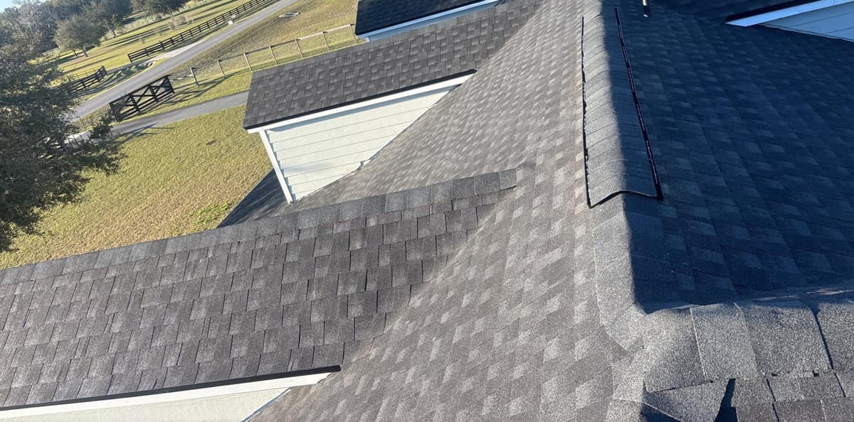 Rooftop view of new charcoal gray shingles, dormer roofs and a ridge vent on a High Springs home
