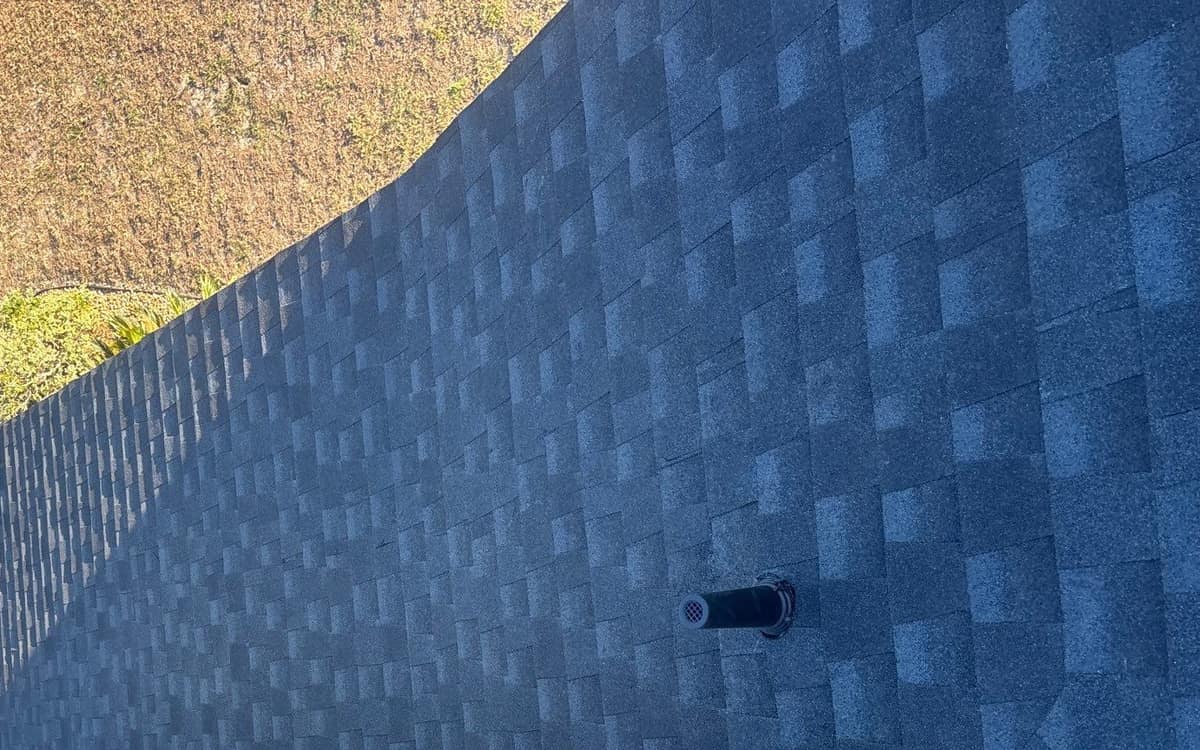 Looking down at a black vent pipe with a screened cap on the High Springs roof
