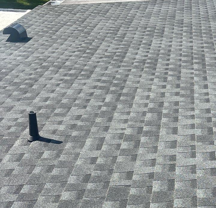 Black plumbing vent pipe and a low hooded vent set into the new Lady Lake shingles