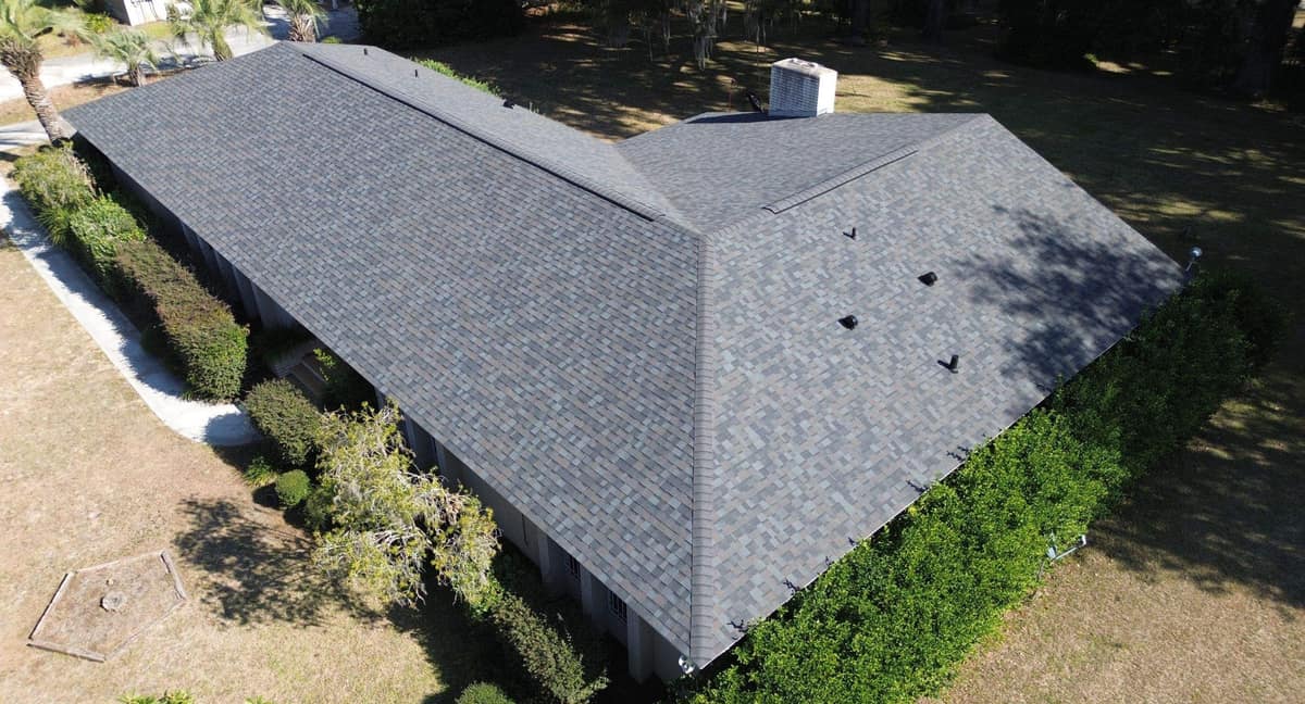 Drone view of the new shingle roof on an L-shaped brick ranch home in Lake City