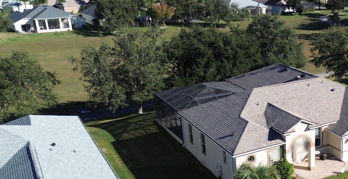 Wide drone view of the Leesburg home beside a long open green dotted with big oaks