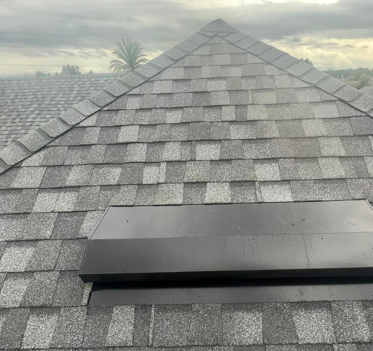 Close view of a black off-ridge vent below a hip peak on the Newberry home