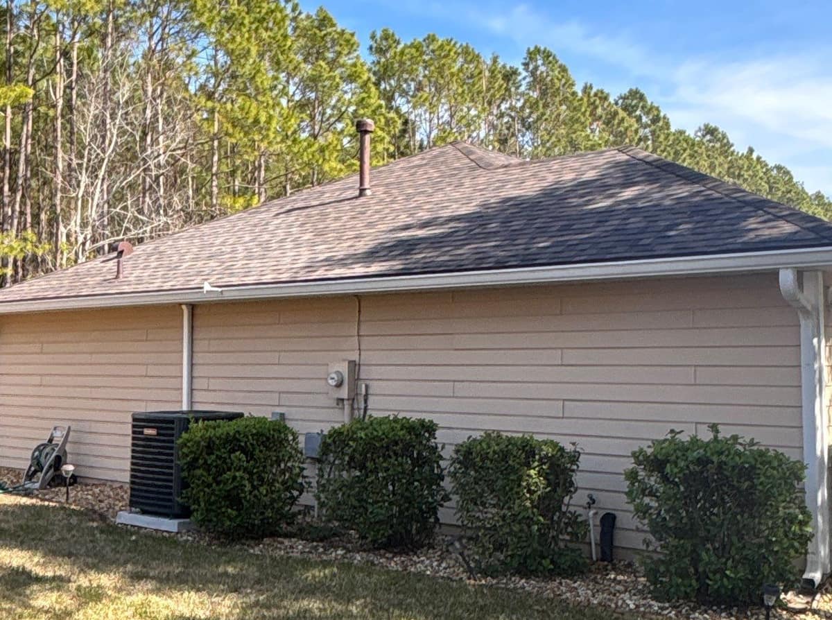 Garage side of the Newberry house with its hip roof and a tall brown vent stack