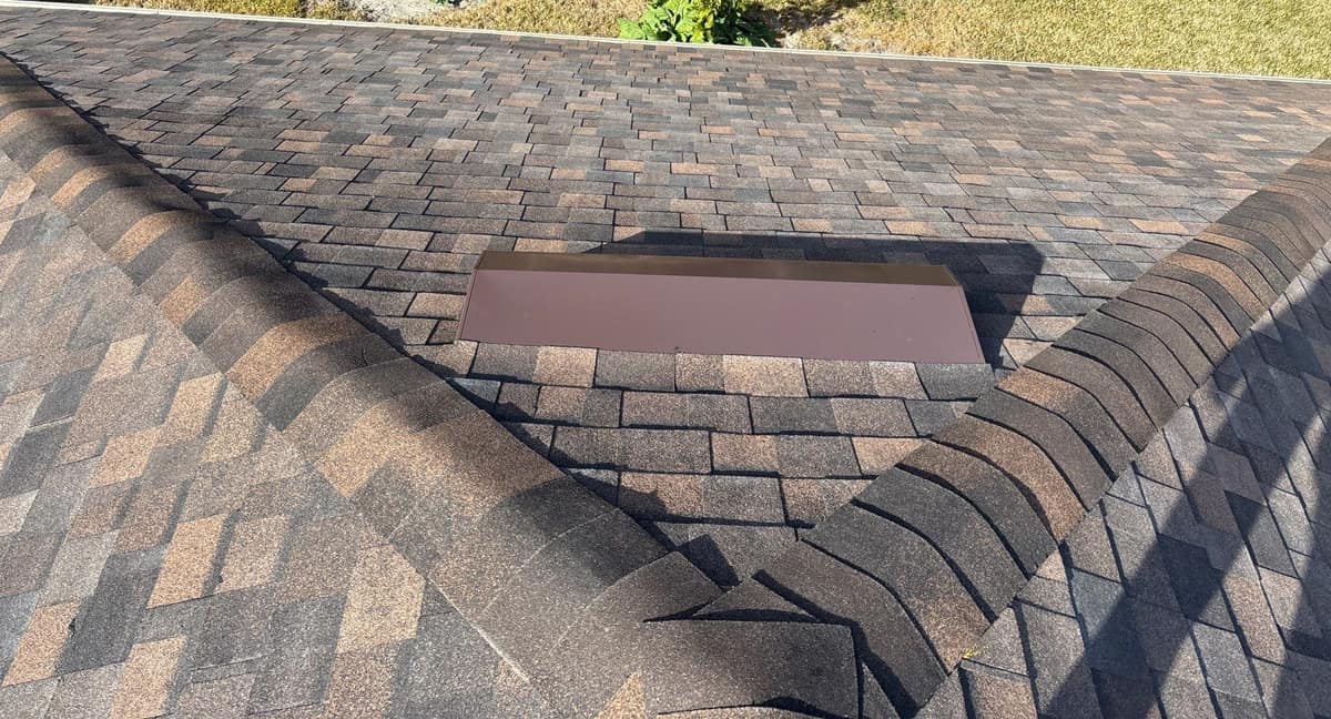 Long brown low-profile vent set just below two hip ridges on the Newberry roof