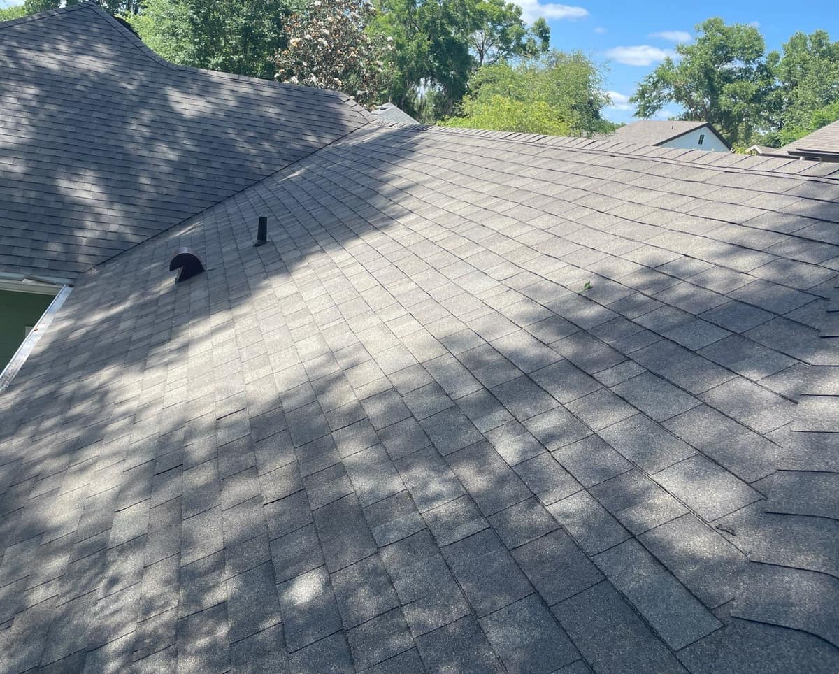 Rear slopes of the new gray-brown shingle roof on a Newberry home, with a hood vent