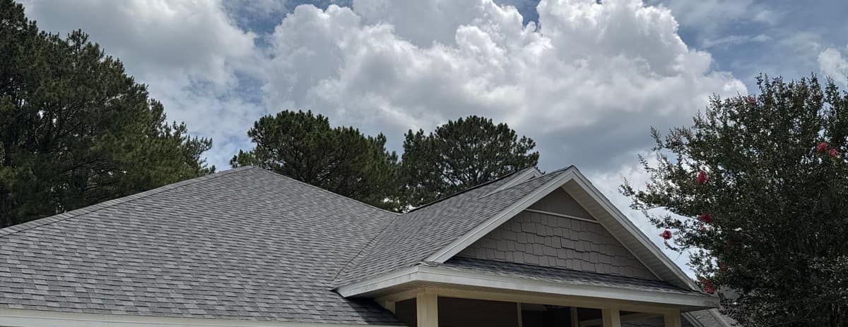 Front of the single-story home in Newberry with its new gray roof, porch gable and tall pines