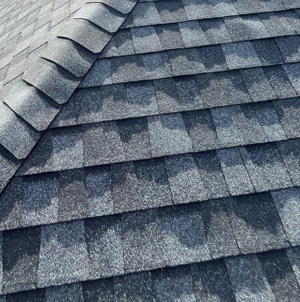 Thick hip cap shingles stepping up a hip line over the gray field shingles in Newberry