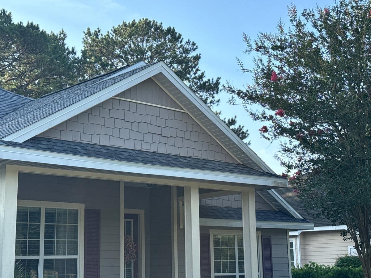 Porch gable with shake-style siding under the new roof, a crape myrtle in bloom beside it in Newberry