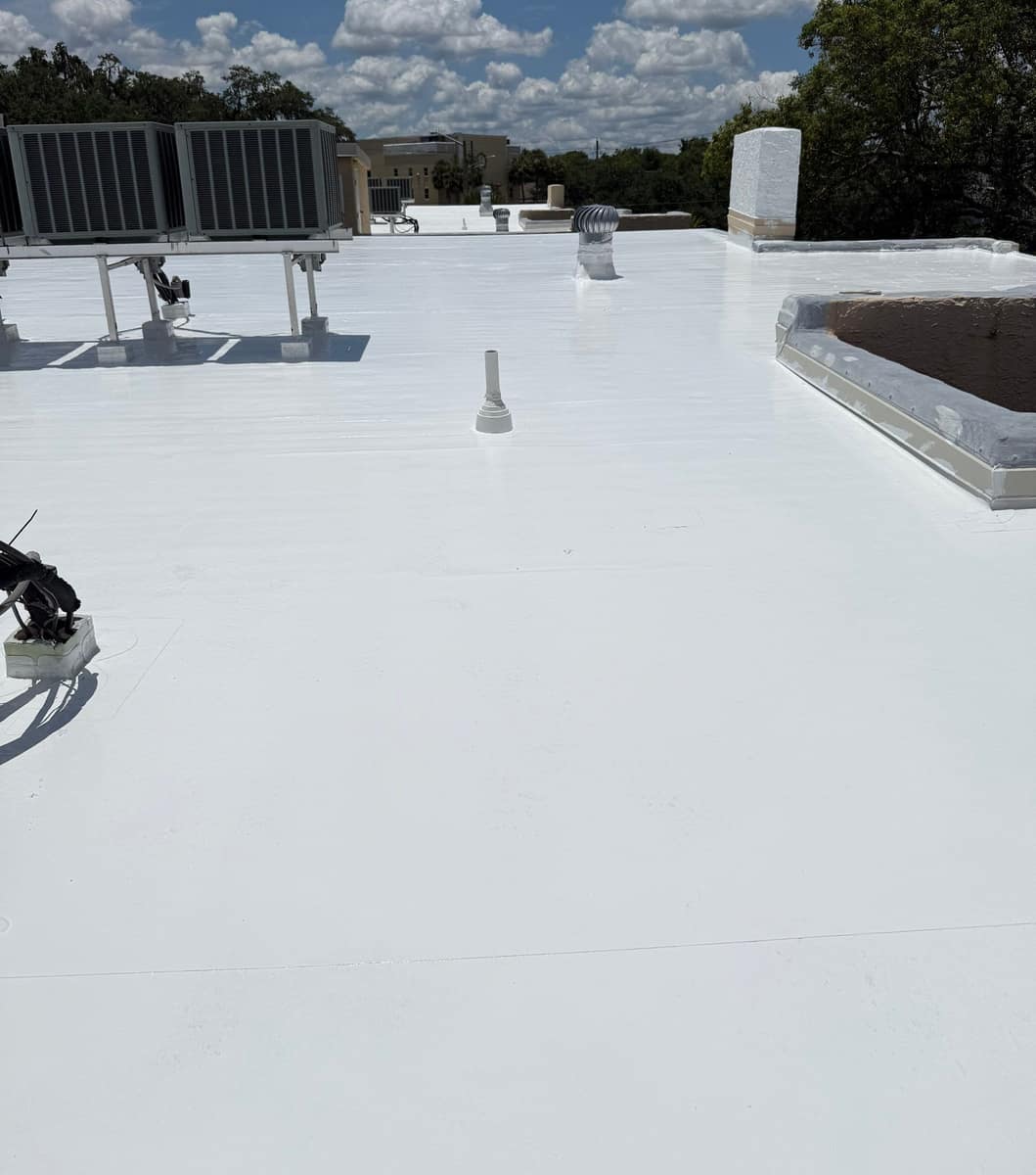 White silicone coated flat roof in Ocala with a rack of AC condensers and a turbine vent