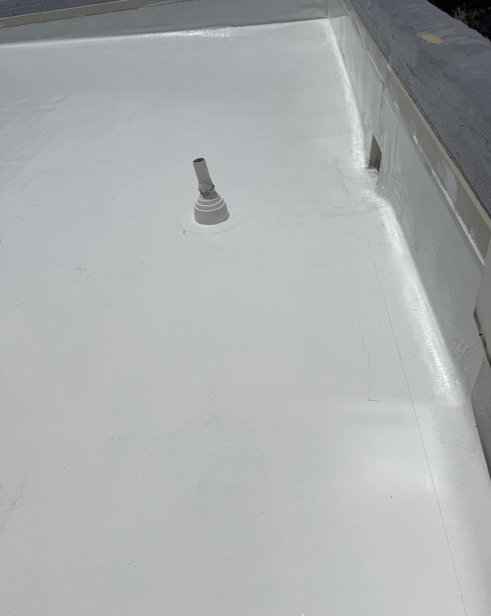 Stepped pipe flashing and a scupper at the base of a parapet wall in Ocala