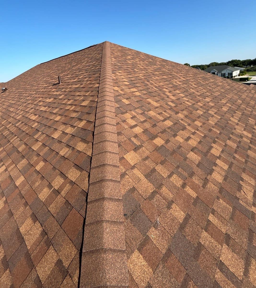 Looking up a hip capped in brown shingles to the peak of the new Ocala roof