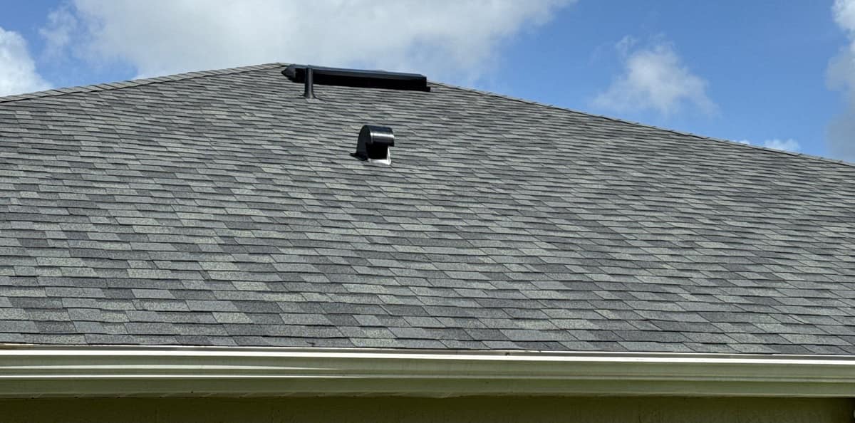 Back slope of the new gray shingle roof in Ocala, with a hooded vent below the peak
